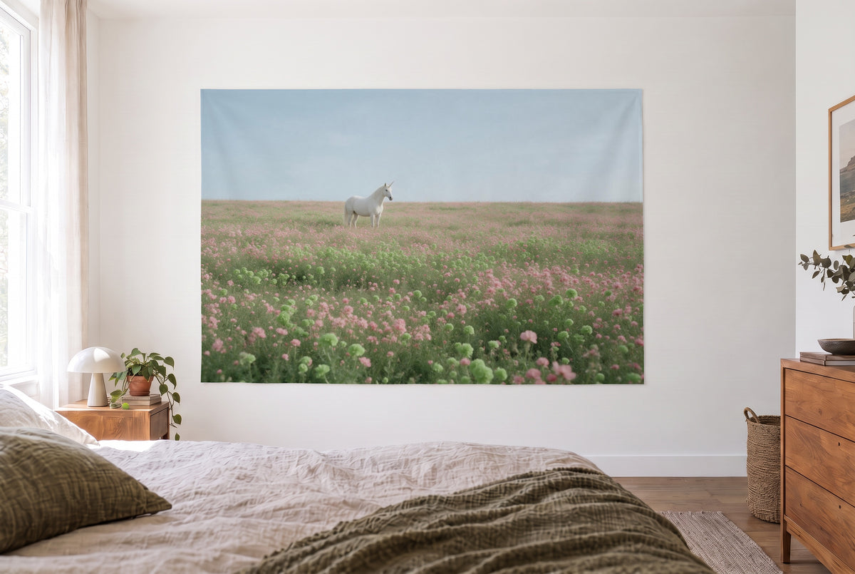 Tenture murale licorne prairie fleurie dans la chambre claire face au lit, commode en bois à droite – rose et vert