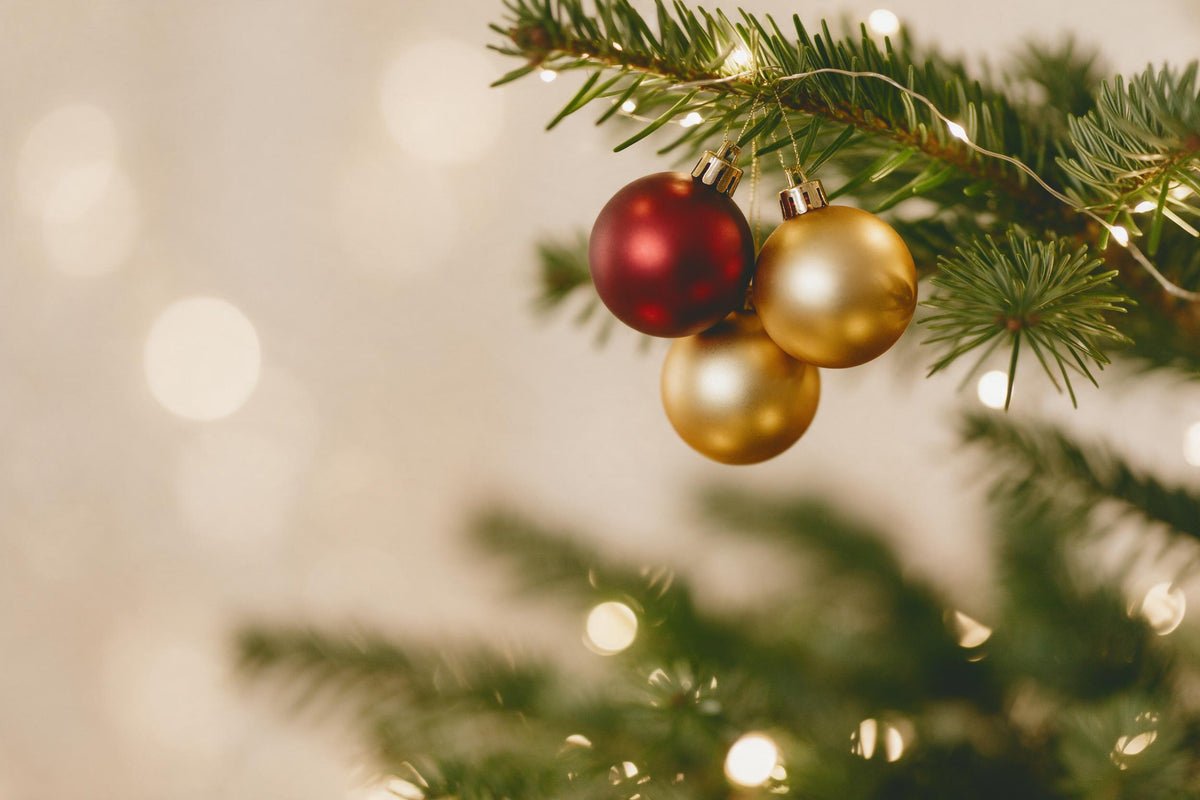 Noël en rouge et or : trois boules à droite sur une branche de sapin avec guirlande, tenture murale imprimée sur tissu
