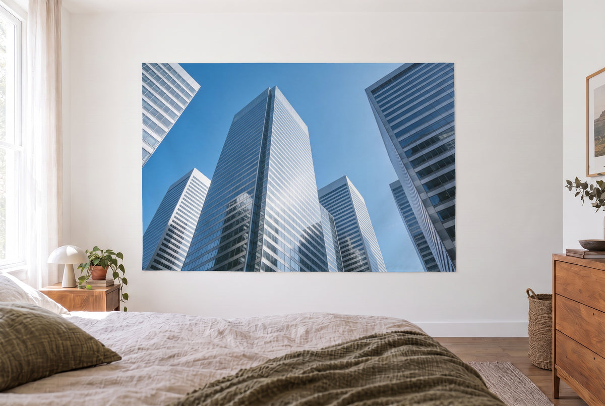 Wandtuch Architektur-Glasfassaden zum Himmel im hellen Schlafzimmer gegenüber dem Bett, rechts eine Holzkommode – Blau