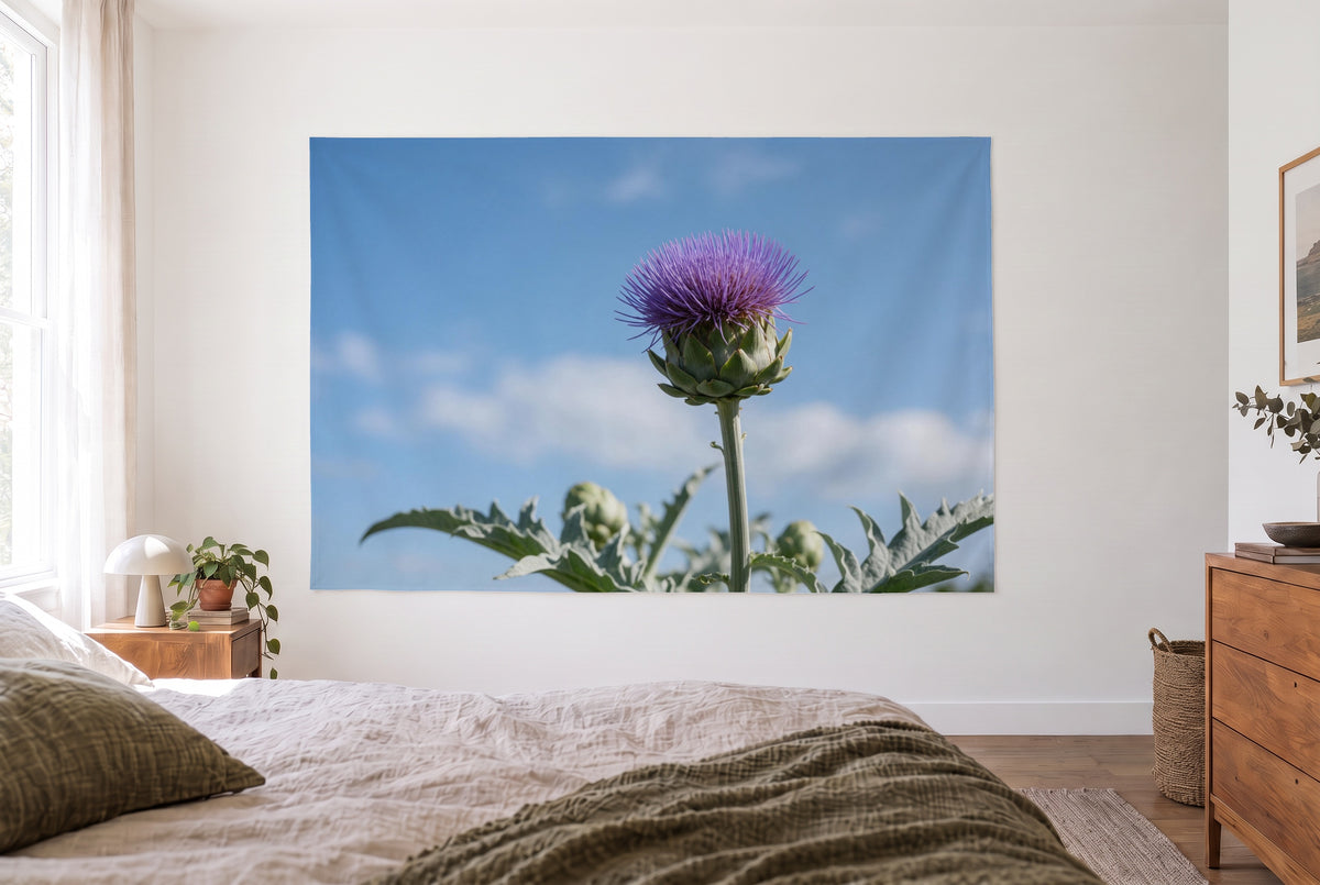 Artichoke flower against a summer sky tapestry in a bright bedroom opposite the bed, wooden dresser on the right