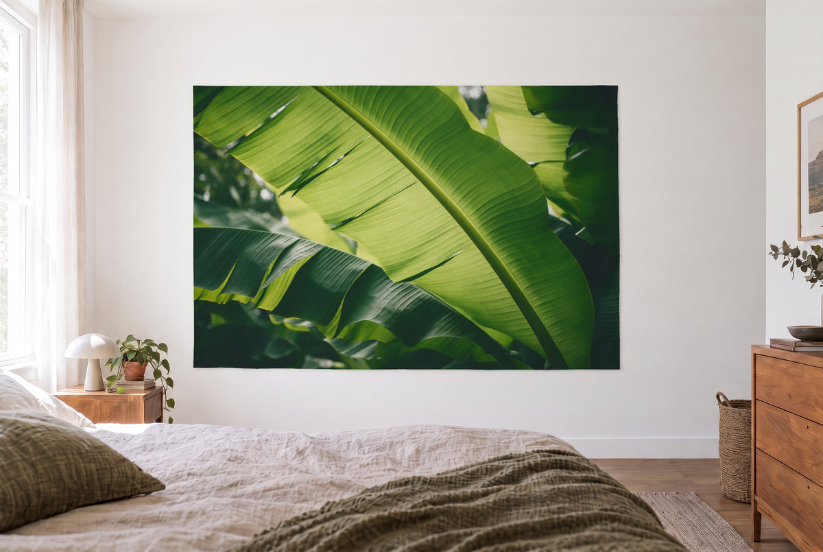 Wandtuch Tropische Bananenblätter im hellen Schlafzimmer gegenüber dem Bett, rechts eine Holzkommode – Grün und Gelb