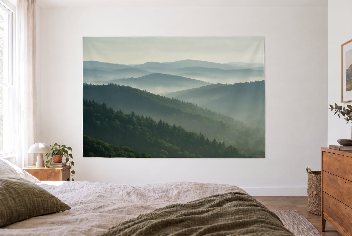 Wandtuch Bewaldete Hügel in Dunstschichten im hellen Schlafzimmer gegenüber dem Bett, rechts eine Holzkommode – Grün