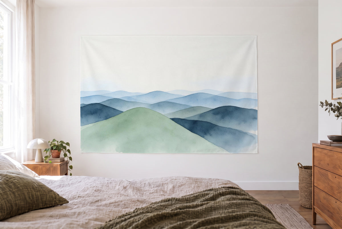Tapiz colinas azules en acuarela en dormitorio claro frente a la cama, cómoda de madera a la derecha – azul y verde