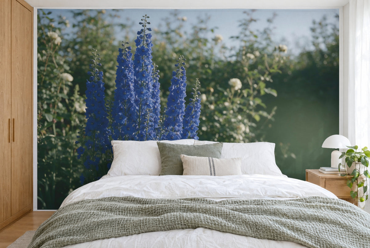 XXL printed fabric: six blue delphinium spikes on the left, white flowers and foliage, filling the wall behind the bed
