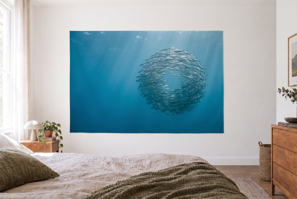School of fish in the blue sea tapestry in a bright bedroom opposite the bed, wooden dresser at right – blue and turquoise