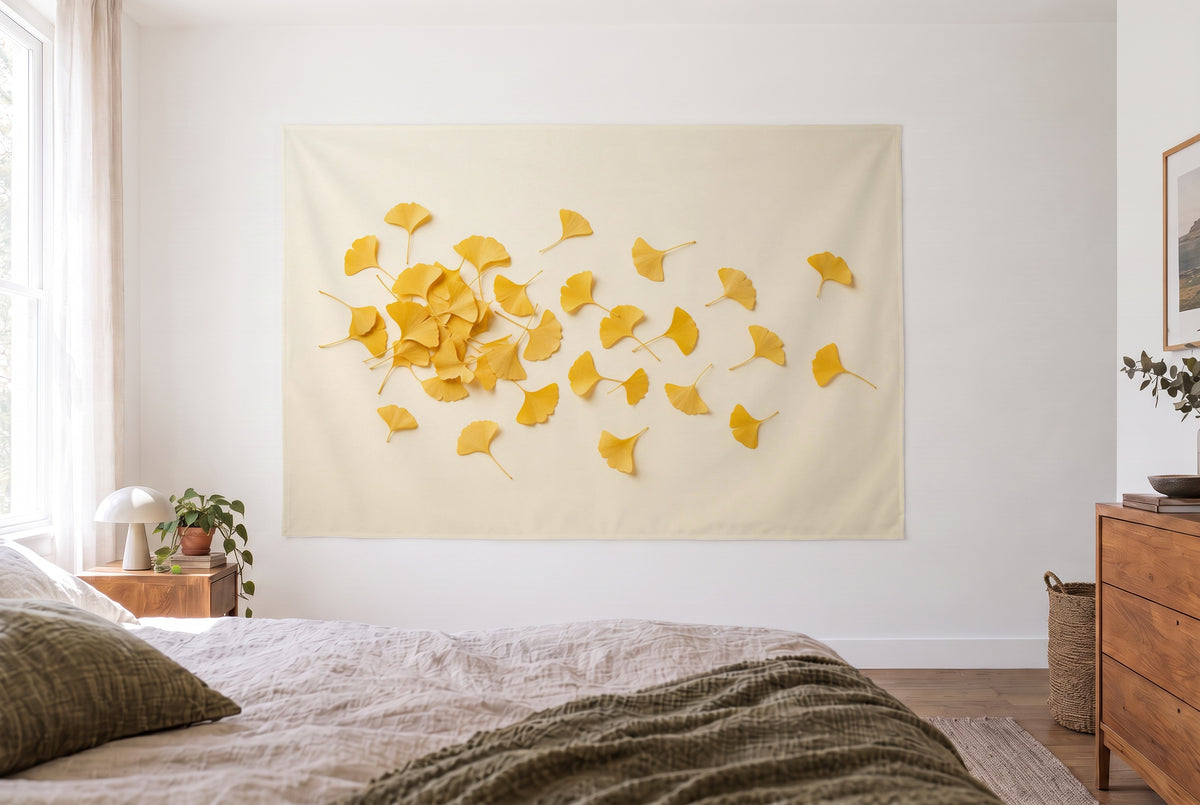 Wandtuch Goldene Ginkgoblätter im hellen Schlafzimmer gegenüber dem Bett, rechts eine Holzkommode – Gelb und Creme