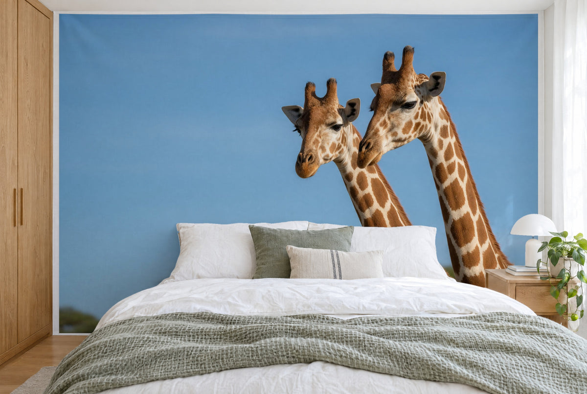 XXL printed fabric: two giraffe heads at right against a wide blue sky, filling the wall behind the bed