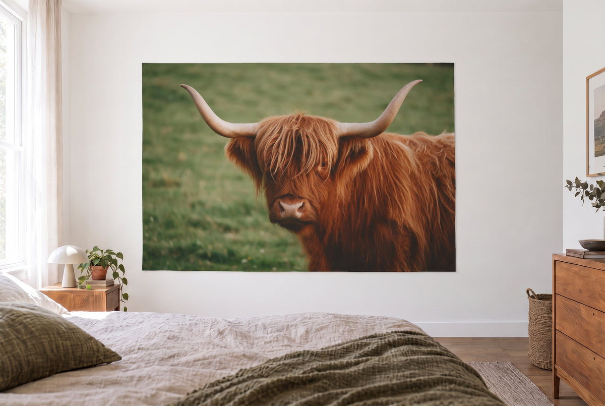 Highland cow portrait tapestry in the bright bedroom opposite the bed, wooden dresser at right – brown and green