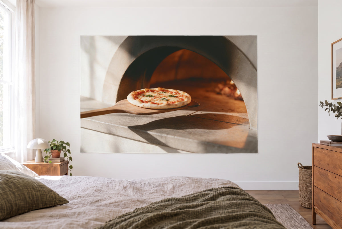 Tapiz pizza de horno de leña en la pala en un dormitorio claro frente a la cama, cómoda de madera a la derecha – rojo y beige