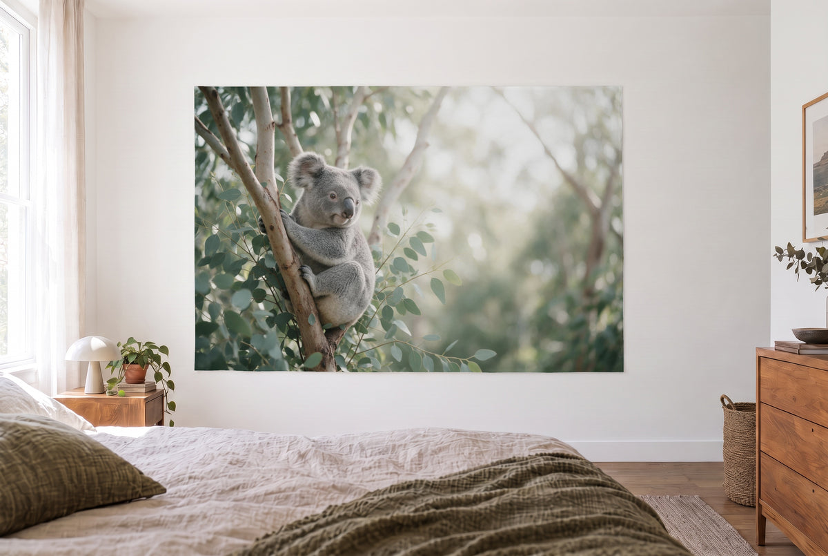 Wandtuch Koala im Eukalyptusbaum im hellen Schlafzimmer gegenüber dem Bett, rechts eine Holzkommode – Grau und Grün