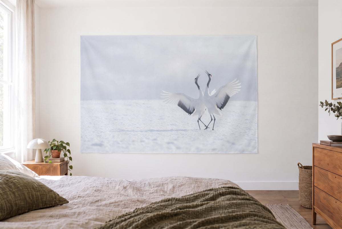 Wandtuch Kraniche im Schnee im hellen Schlafzimmer gegenüber dem Bett, rechts eine Holzkommode – Weiss und Grau