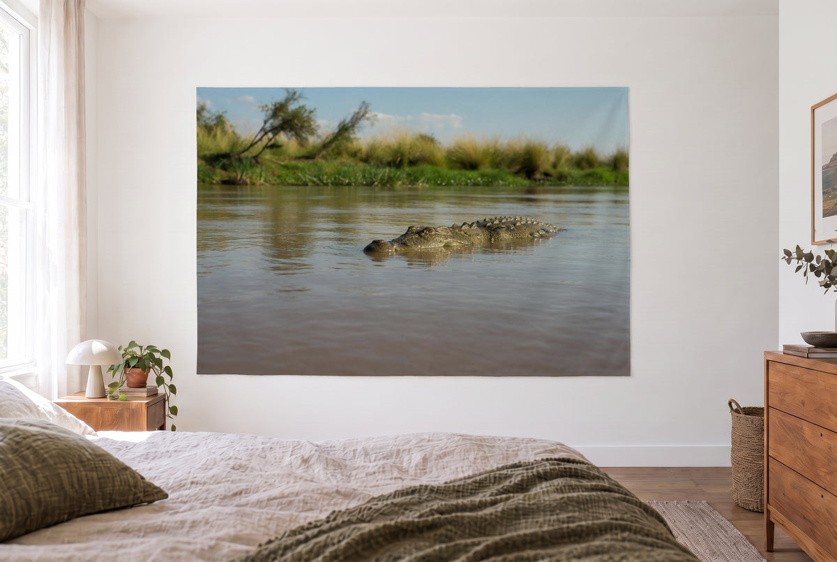 Wandtuch Krokodil im Fluss im hellen Schlafzimmer gegenüber dem Bett, rechts eine Holzkommode – Grün und Braun