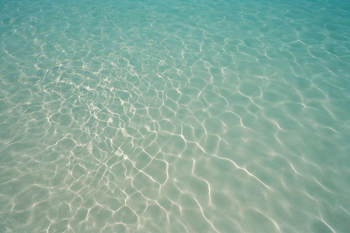 Türkises Wasser mit feinem Lichtnetz links über hellem Sandgrund, als Wandtuch, auf Stoff gedruckt – Blau, Grün und Beige