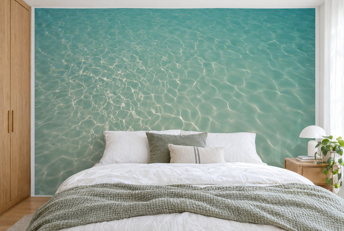 Bedruckter Stoff im XXL-Format: helles Lichtnetz links auf klarem Wasser, rechts ruhiger Sand, wandfüllend hinter dem Bett