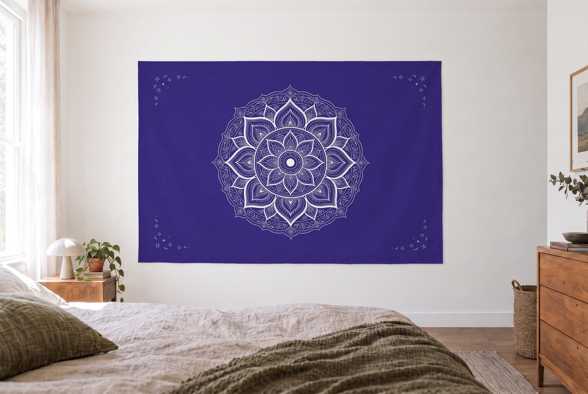 Tenture mandala indigo et blanc dans une chambre claire face au lit, une commode en bois à droite – indigo