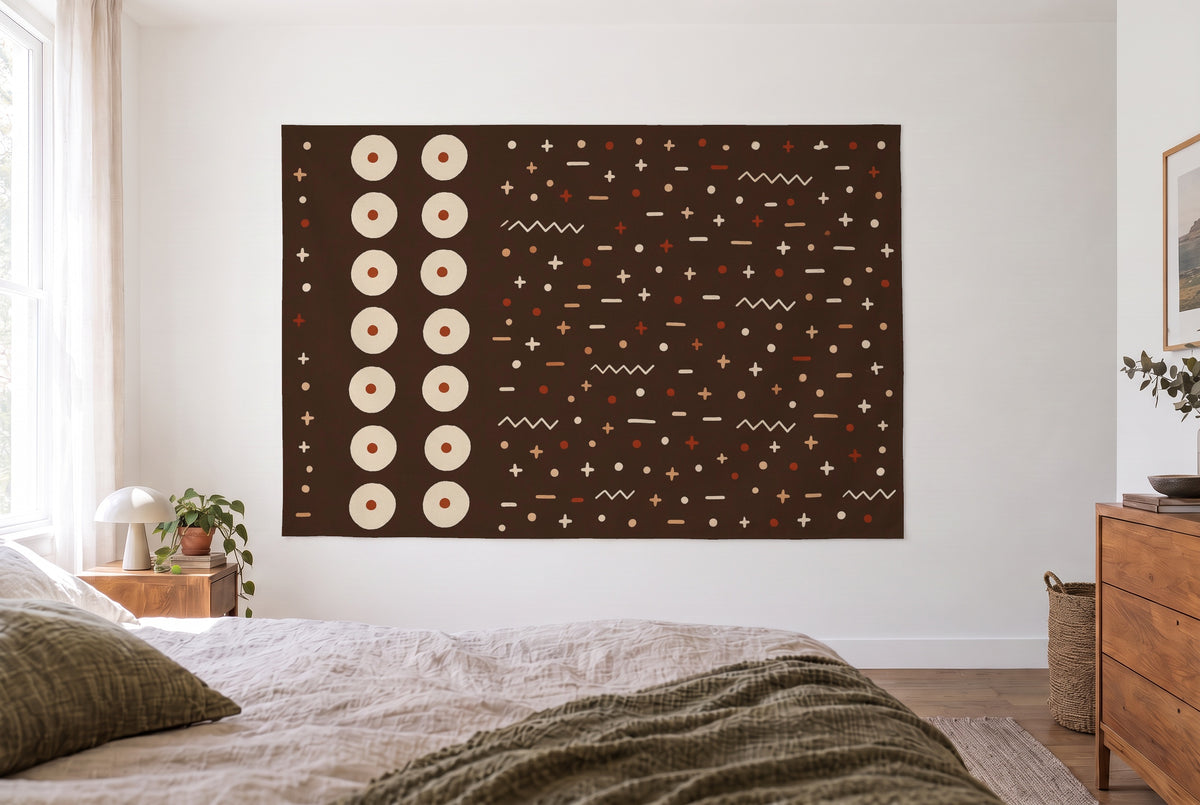 Wandtuch Mudcloth-Muster in Braun und Creme im hellen Schlafzimmer gegenüber dem Bett, rechts eine Holzkommode – Rostrot