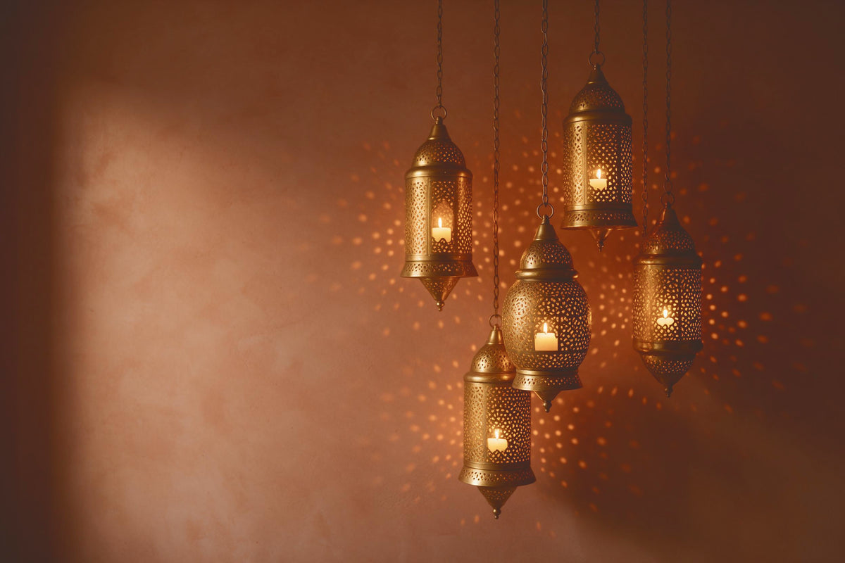 Oriental brass lanterns with pierced pattern at right in front of a terracotta wall, tapestry printed on fabric – gold, brown