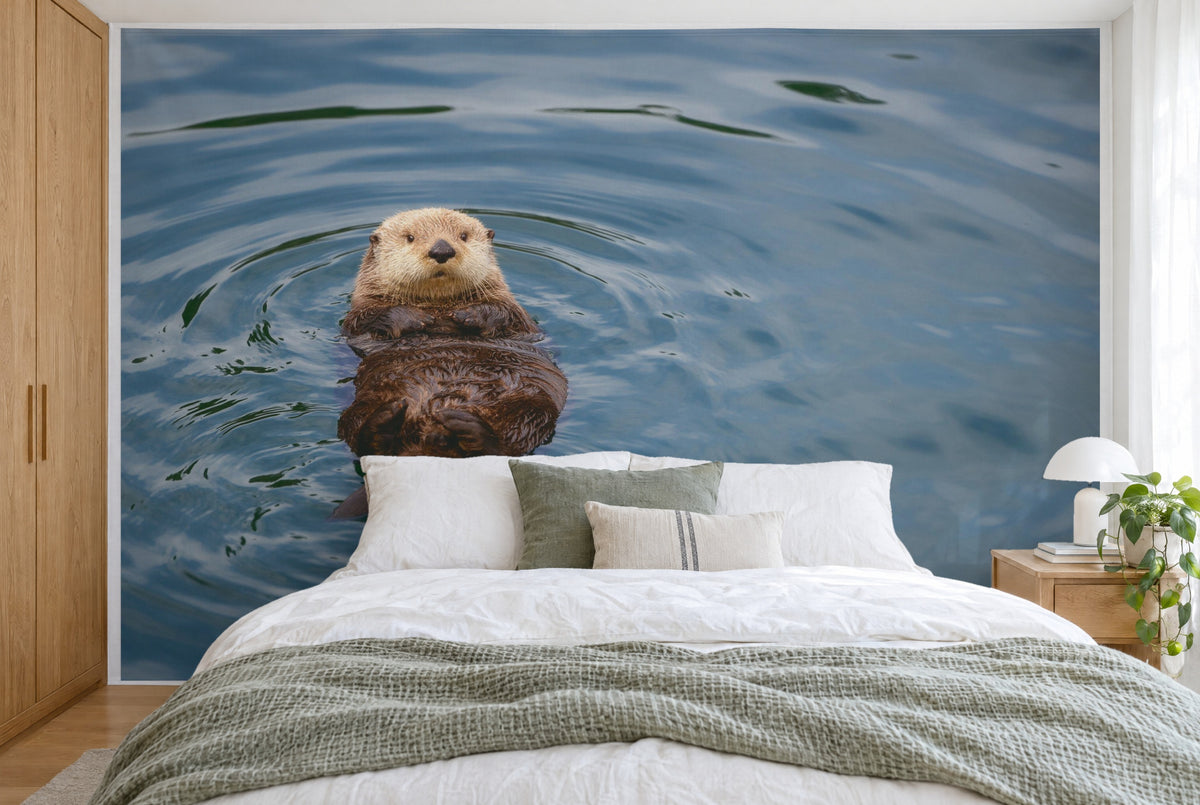 Bedruckter Stoff im XXL-Format: Otter links auf dem Rücken in ruhigem Wasser mit Wasserringen, wandfüllend hinter dem Bett
