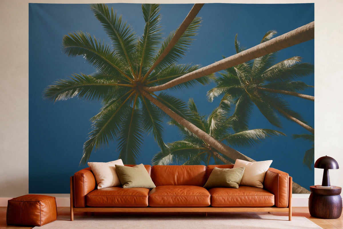 Tenture murale XXL Palmiers sous un ciel bleu en déco murale dans un salon chaleureux au-dessus du canapé en cuir