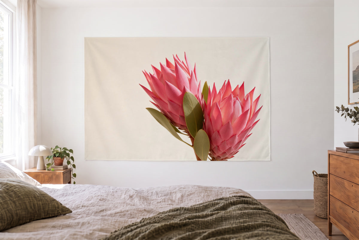 Wandtuch Protea-Blüten in Rosa im hellen Schlafzimmer gegenüber dem Bett, rechts eine Holzkommode – Rosa und Creme
