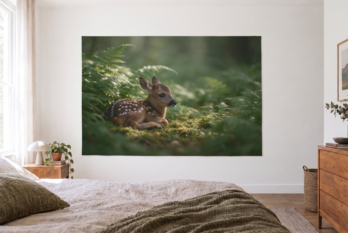 Wandtuch Rehkitz im Farn im hellen Schlafzimmer gegenüber dem Bett, rechts eine Holzkommode – Grün und Braun