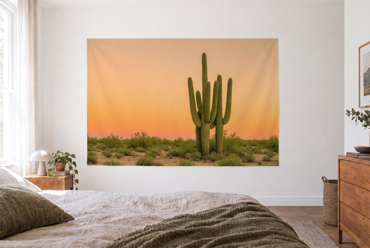 Tenture cactus saguaro dans le désert, chambre claire face au lit, commode en bois à droite – vert et orange