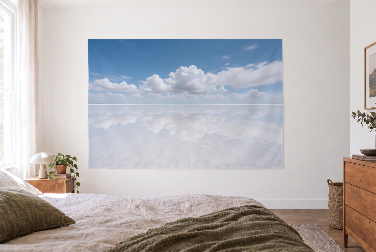 Salt lake mirrors the sky tapestry in the bright bedroom opposite the bed, wooden dresser at right – blue and white