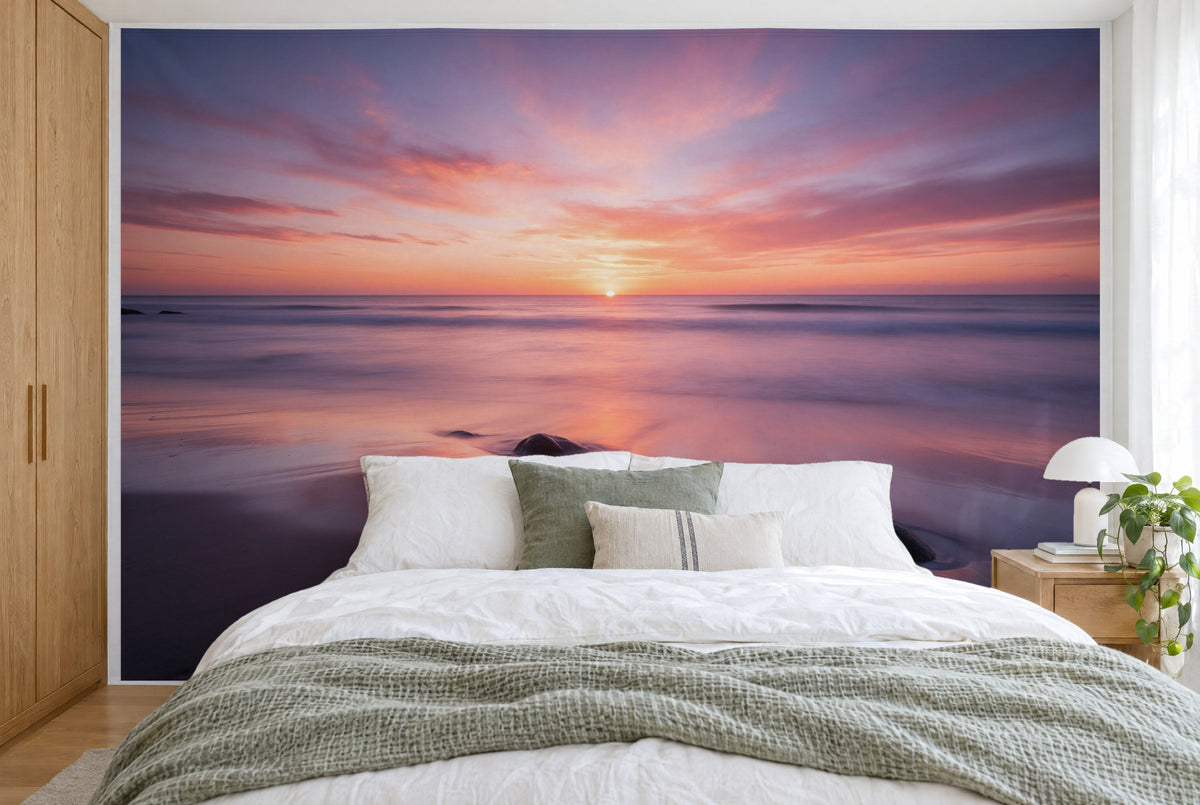 Bedruckter Stoff im XXL-Format: Sonne mittig am Horizont über glattem Meer, rosa Wolkenhimmel, wandfüllend hinter dem Bett