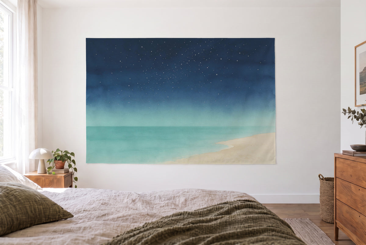 Wandtuch Sternenhimmel über dem Meer im hellen Schlafzimmer gegenüber dem Bett, rechts eine Holzkommode – Blau und Beige