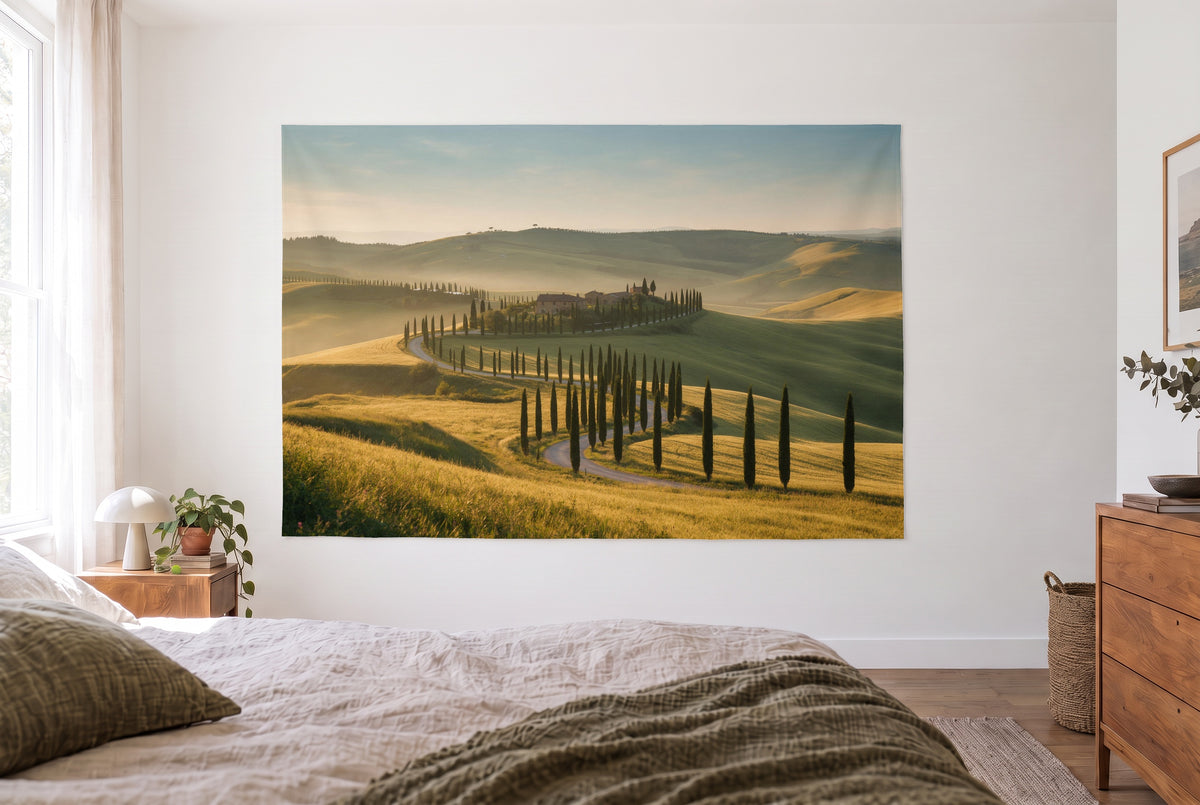 Tenture collines de Toscane et cyprès dans une chambre claire face au lit, commode en bois à droite – or et vert