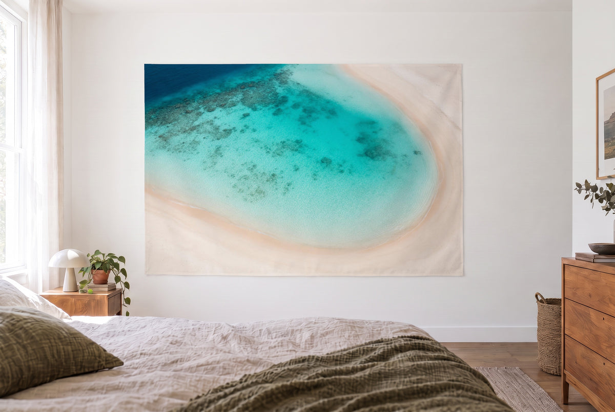 Tenture murale plage tropicale vue du ciel dans la chambre claire face au lit, commode en bois à droite – turquoise et beige