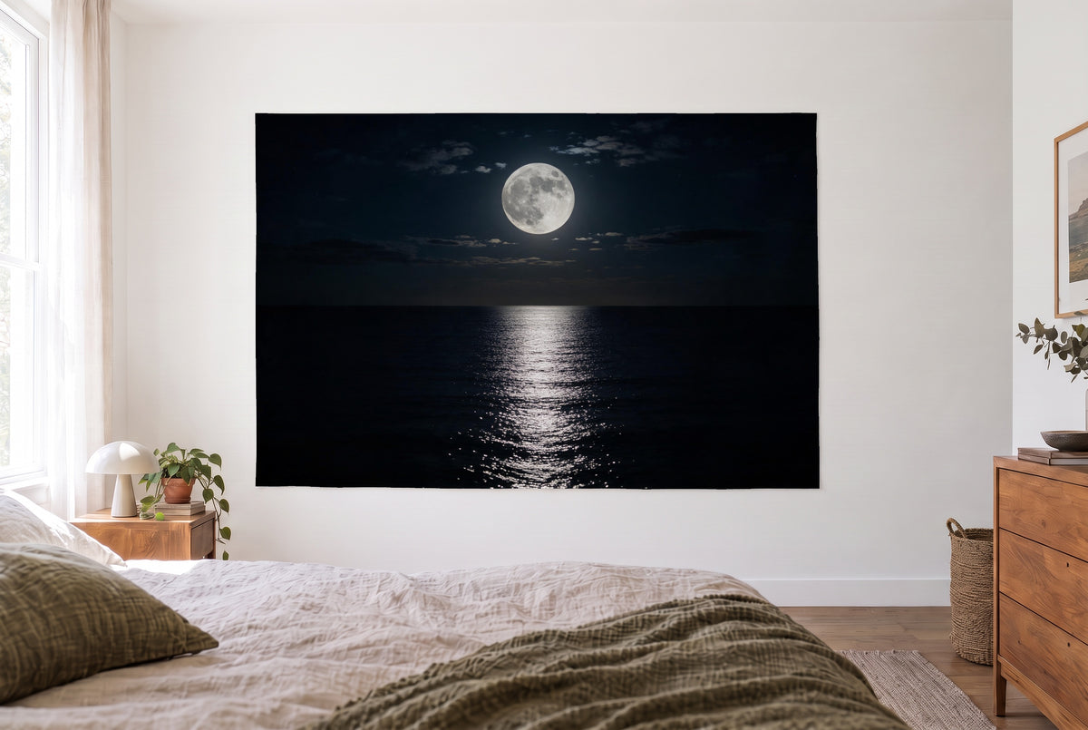 Tenture pleine lune sur la mer dans une chambre claire face au lit, commode en bois à droite – bleu nuit et argent