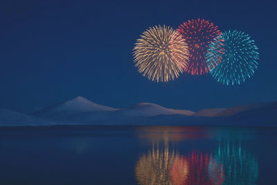 Feuerwerk in Gold, Rot und Türkis über einem stillen Bergsee mit Spiegelung, als Wandtuch, auf Stoff gedruckt – Nachtblau