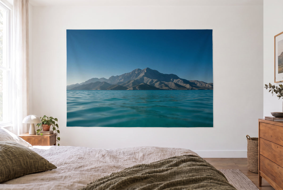 Tenture murale montagnes mer dans la chambre claire face au lit, commode en bois à droite – bleu turquoise