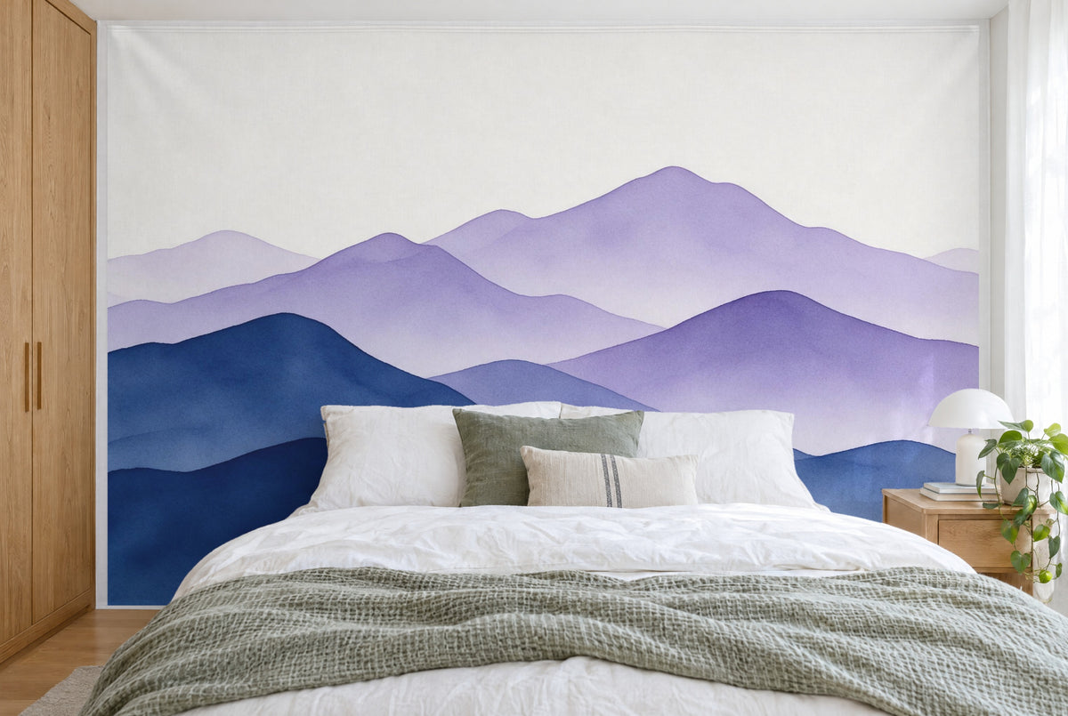XXL printed fabric: layered mountain ranges in blue and violet, cream-white sky, filling the wall behind the bed