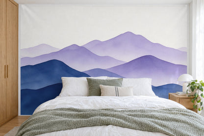 XXL printed fabric: layered mountain ranges in blue and violet, cream-white sky, filling the wall behind the bed