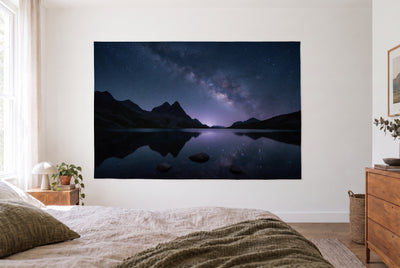 Tapiz lago de montaña de noche con Vía Láctea en dormitorio claro frente a la cama, cómoda a la derecha – azul noche