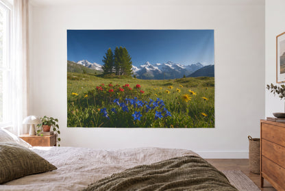 Tenture murale prairie alpine fleurs dans la chambre claire face au lit, commode en bois à droite – bleu vert