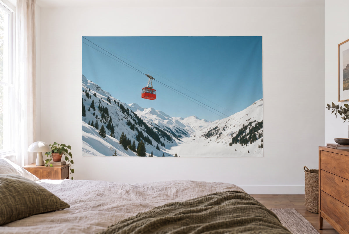 Tenture murale cabine téléphérique vallée dans la chambre claire face au lit, commode en bois à droite – rouge et bleu