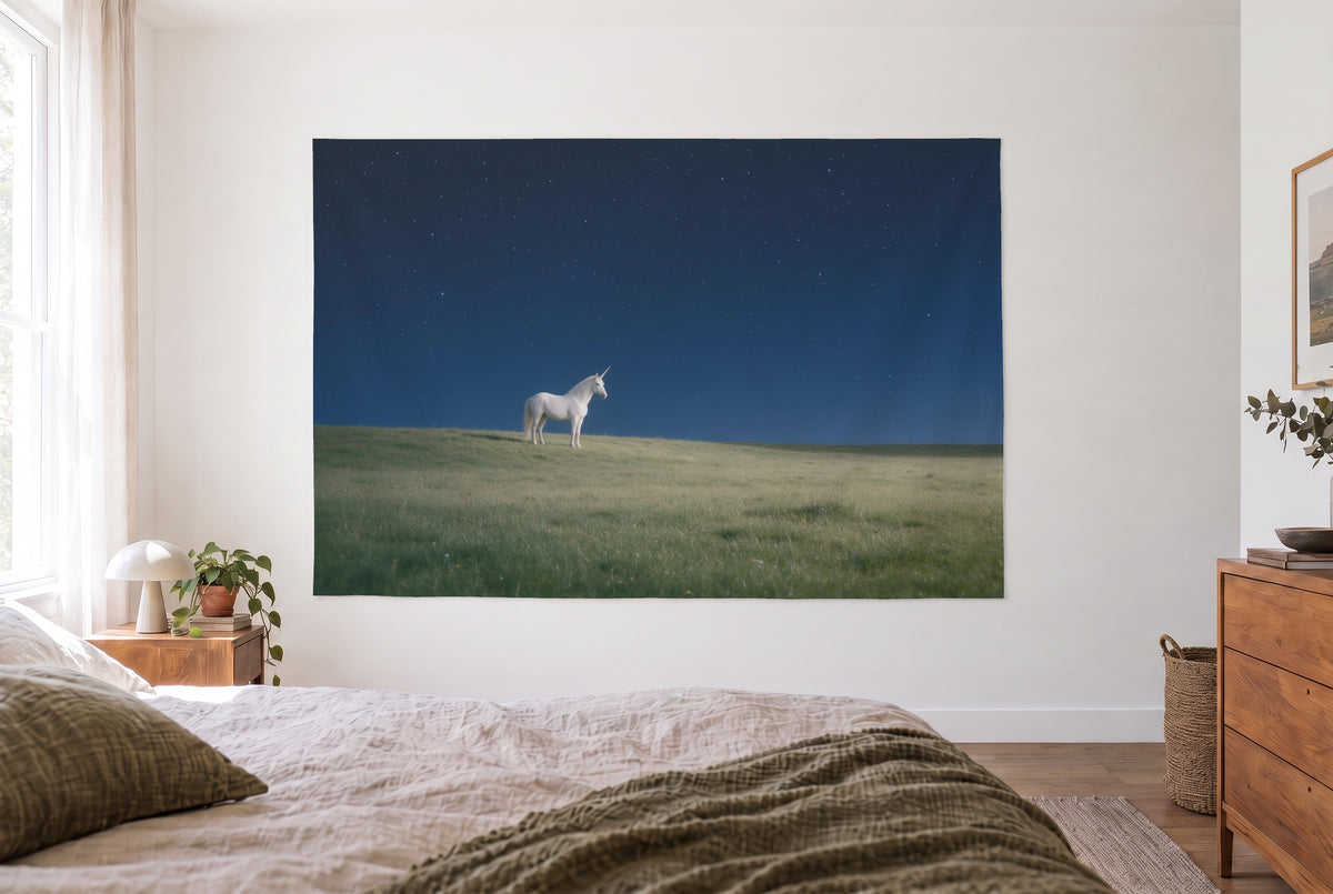 Tenture murale licorne sous le ciel étoilé dans la chambre claire face au lit, commode en bois à droite – bleu et vert