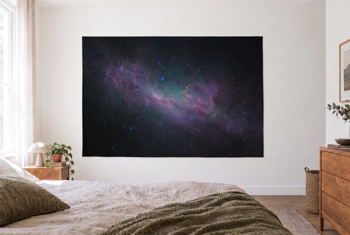 Tenture galaxie et nébuleuse étoilée dans une chambre claire face au lit, commode en bois à droite – violet et noir
