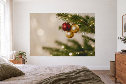 Tenture boules de Noël sur branche de sapin dans la chambre claire face au lit, commode en bois à droite – rouge et or