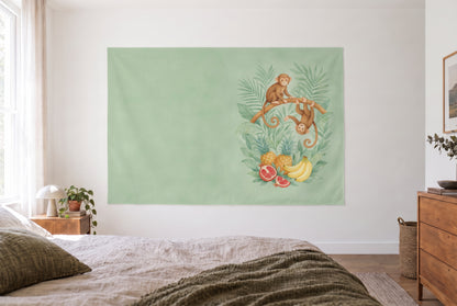 Tenture singes aux fruits tropicaux dans la chambre claire face au lit, commode en bois à droite – vert et jaune
