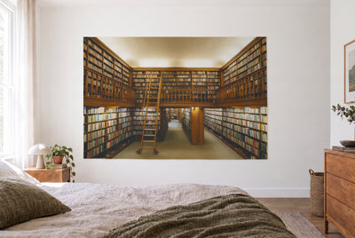 Tenture bibliothèque ancienne avec galerie dans la chambre claire face au lit, commode en bois à droite – brun et or