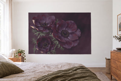 Anemones on a dark background tapestry in a bright bedroom opposite the bed, wooden dresser on the right – violet and green