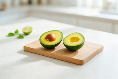 Dos mitades de aguacate cortadas con hueso sobre una tabla de roble claro, tapiz impreso en tela – verde y amarillo