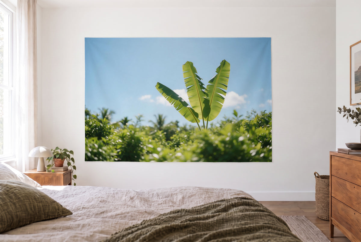 Banana leaves in backlight tapestry in a bright bedroom opposite the bed, wooden dresser on the right – green and blue