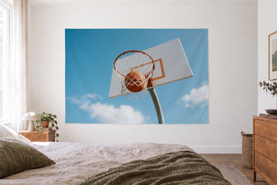 Basketball in the hoop tapestry in a bright bedroom opposite the bed, wooden dresser on the right – orange and blue