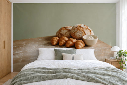 Bedruckter Stoff im XXL-Format: Brote und Croissants rechts der Mitte vor salbeigrüner Wand, wandfüllend hinter dem Bett