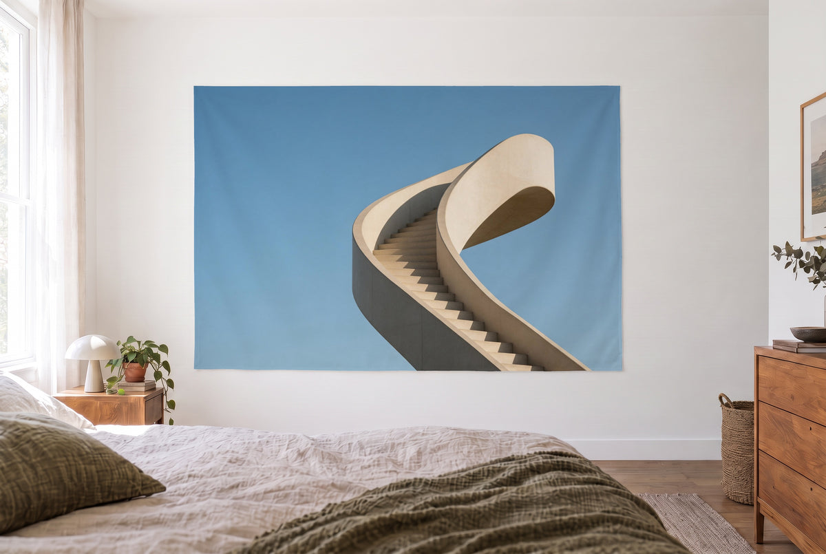 Wandtuch Geschwungene Betontreppe im hellen Schlafzimmer gegenüber dem Bett, rechts eine Holzkommode – Beige und Blau